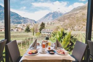 una mesa con comida y vistas a las montañas en Hotel Wessobrunn, en Merano