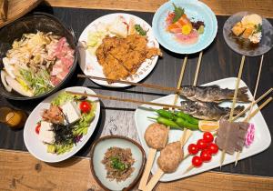 une table recouverte de plaques de nourriture et de baguettes dans l'établissement Asama Onsen FAN! MATSUMOTO, à Matsumoto