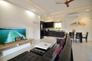 ein Wohnzimmer mit einem Sofa und einem Flachbild-TV in der Unterkunft Villa Nokyoong in Hua Hin