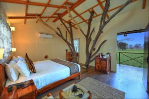 a bedroom with a bed and a tree in it at Bagh Serai - Rustic Cottage with Private Pool in Sawāi Mādhopur