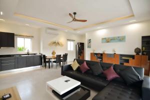 a living room with a black couch and a kitchen at Villa Nokyoong in Hua Hin
