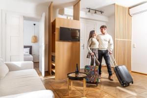 un uomo e una donna in piedi in un soggiorno con i loro bagagli di Apartments am Glockenspielplatz a Graz