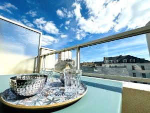 een dienblad met glazen op een tafel op een balkon bij Appartement rénové avec goût et idéalement situé à deux pas du remblai in Les Sables-dʼOlonne