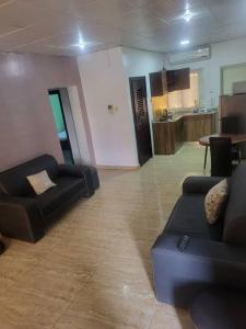 ein Wohnzimmer mit schwarzen Sofas und eine Küche in der Unterkunft KINGS AVENUE SERVICE APARTMENTS in Lagos