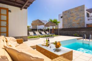een patio met een tafel en stoelen naast een zwembad bij Villa Dacil in Playa Blanca