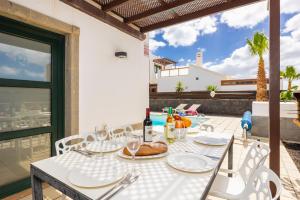 einen weißen Tisch mit Tellern und Weingläsern auf einer Terrasse in der Unterkunft Villa Ariel in Playa Blanca