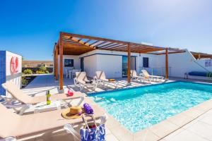 einen Pool mit Liegestühlen und ein Haus in der Unterkunft Villa Beyond in Playa Blanca