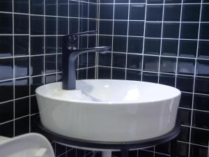 a sink in a bathroom with a black tiled wall at Explorers Hub in Kampala