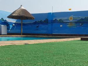 a swimming pool with an umbrella and a mural at MKHUZE INN in Mkuze