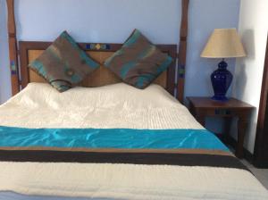 - un lit avec une tête de lit en bois et 2 oreillers dans l'établissement Fortuna Beach, à Flic-en-Flac