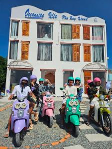 eine Gruppe von Personen, die vor einem Gebäude Motorrad fahren in der Unterkunft Oceanside Villa Phuquy Island in Cu Lao Thu