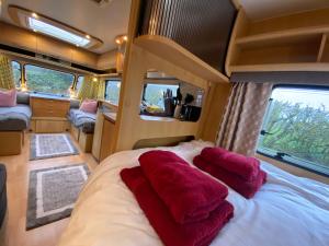 Una cama grande en una caravana con almohadas rojas. en Cosy Caravan on Luxury Campsite, en Hulme End