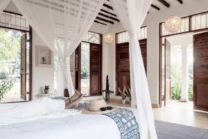 a woman laying on a bed in a room with windows at Tarangau Retreat in Kilifi