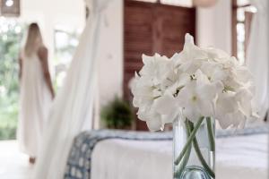 wazon wypełniony białymi kwiatami siedzącymi na stole w obiekcie Tarangau Retreat w mieście Kilifi