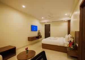 een slaapkamer met een bed en een tafel en een televisie bij Meghalaya Hotel in Visakhapatnam