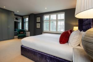 een slaapkamer met een groot bed met rode en witte kussens bij Veeve - Parkside Purity in Londen