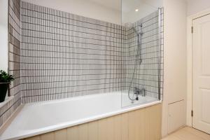 a bath tub with a shower in a bathroom at Veeve - Parkside Purity in London