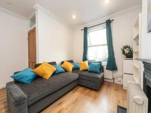 a living room with a gray couch with blue and yellow pillows at Pass the Keys Modernised family-friendly cottage in Surbiton