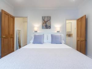- une chambre avec un grand lit blanc et des oreillers bleus dans l'établissement Pass the Keys Modernised family-friendly cottage, à Surbiton