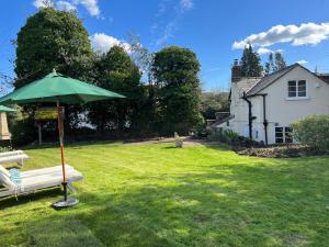 a green umbrella sitting in the yard of a house at Luxury Cottage with Garden in Bredon