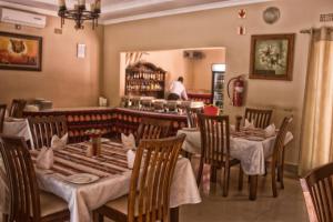 un restaurant avec des tables et des chaises et une personne en arrière-plan dans l'établissement Waterfalls hotel (Lusaka), à Lusaka