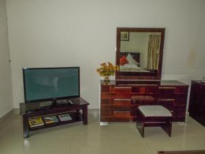 a living room with a tv and a chair and a mirror at Waterfalls hotel (Lusaka) in Lusaka