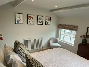 1 dormitorio con 1 cama y algunas fotos en la pared en Luxury Cottage with Garden en Bredon