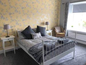 1 dormitorio con cama y pared amarilla en Meikle Farm Cottage, en Westruther
