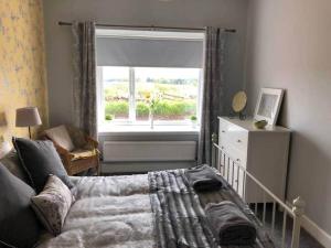 ein Schlafzimmer mit einem Kinderbett und einem großen Fenster in der Unterkunft Meikle Farm Cottage in Westruther + 2 Fotos