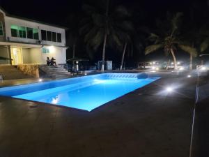 een zwembad verlicht in de nacht bij ELLISA HOSPITALITY and SPA in Accra