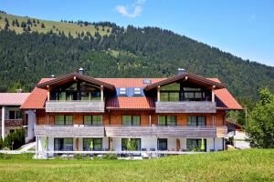 a large building with a mountain in the background at Alpin Lodges - Moderne Appartements mit Zugang zu 3000 qm SPA Panoramahotel Oberjoch in Bad Hindelang