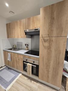 a kitchen with wooden cabinets and a stove top oven at Studio 2022 terrasse parking 5 min d'Annecy in Poisy