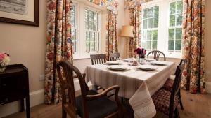 uma sala de jantar com uma mesa com cadeiras e janelas em Birks Stable Cottage em Hexham