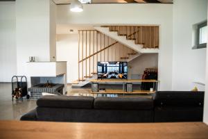 ein Wohnzimmer mit schwarzem Sofa und Fernseher in der Unterkunft LaHuzur - Casa de Vacanta - Therme Balotesti & Aeroport Otopeni in Săftica