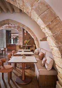 Habitación con mesas, sofás y pared de piedra. en Boutique Hotel Posada Terra Santa, en Palma de Mallorca