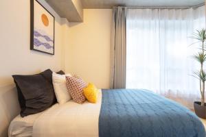 a bedroom with a bed with pillows and a window at Dash Living Kagurazaka in Tokyo