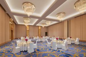 博帕爾的住宿－博帕爾萬怡酒店，宴会厅配有白色的桌椅和吊灯。