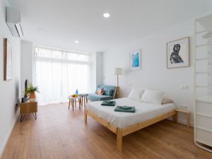 Habitación blanca con cama y sofá en HomeForGuest Estudio Brisa Canteras con terraza, en Las Palmas de Gran Canaria