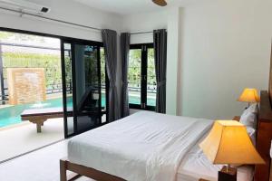 a bedroom with a bed and a view of a pool at Peacefully Rawai 3 Bedrooms Pool Villa in Rawai Beach