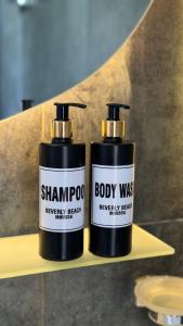 deux bouteilles de shampoing et de gel douche assises sur une étagère dans l'établissement Beverly Beach Mirissa, à Mirissa