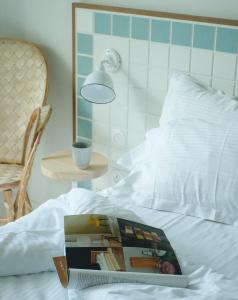 a book on a bed with a lamp and a table at Hotel des Dunes in Cap-Ferret