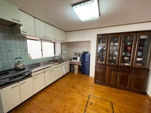 a large kitchen with white cabinets and a wooden floor at YAKUSHIMA YUDOMARI443 in Yudomari