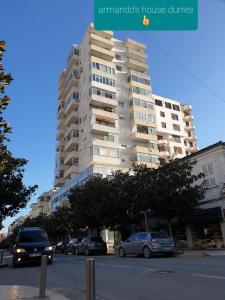 een hoog gebouw met auto's geparkeerd voor het bij armando's house durres in Durrës