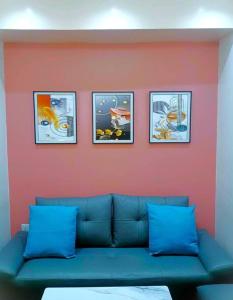 a blue couch against a red wall with four pictures at Apartment-Serviced & Condo Free pool in Quezon City by Mi'Casa in Manila