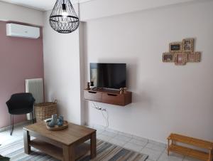 sala de estar con TV en una pared blanca en Όμορφο δίχωρο διαμέρισμα στο κέντρο της πόλης, en Kalamata