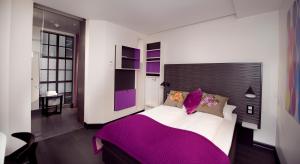 a bedroom with a large bed with purple sheets at Hotel No13 in Bergen