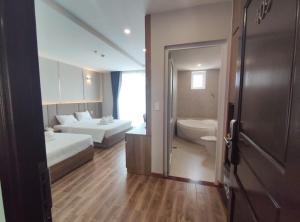 a hotel room with two beds and a bathroom at Ho Tram Golden Hotel in Ho Tram