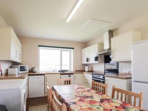 a kitchen with white cabinets and a table with chairs at Loubcroy Farm House in Lairg