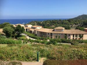 a house on a hill with the ocean in the background at Cap Esterel 2 pièces Climatisé 4-5pers Piscines Parking Draps Wifi in Saint-Raphaël