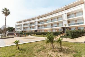 a large white building with palm trees in front of it at Golden Terrace Delight in São Martinho do Porto